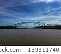 Steel Arch Bridge Spanning Calm River Under Blue Sky Scenic Waterfront Landscape Reflection Travel Infrastructure Landmark 139311740