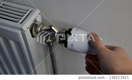 Hand adjusting a thermostatic radiator valve for heating control 139311921