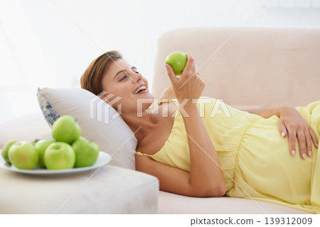 Pregnant woman, apple and smile on sofa for health, nutrition and wellness in living room of apartment. Person, fruit and happy on couch of lounge for relax, pregnancy and healthy diet with vitamins Pregnant woman, apple and smile on sofa for health, nutrition and wellness in living room of apartment. Person, fruit and happy on couch of lounge for relax, pregnancy and healthy diet with vitamins 139312009