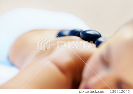 Hot stone, massage and woman back closeup at spa for wellness treatment and detox. Calm, muscle healing recovery and a female person with sleep at resort or hotel with beauty therapist with skincare Hot stone, massage and woman back closeup at spa for wellness treatment and detox. Calm, muscle healing recovery and a female person with sleep at resort or hotel with beauty therapist with skincare 139312045