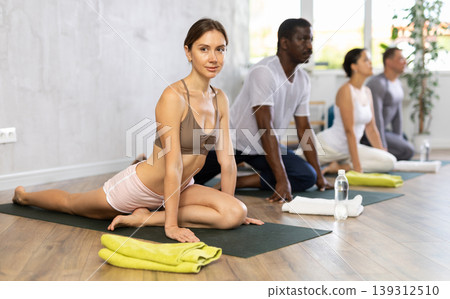 Young female doing cobra pose for health care and wellness with group together at yoga studio 139312510