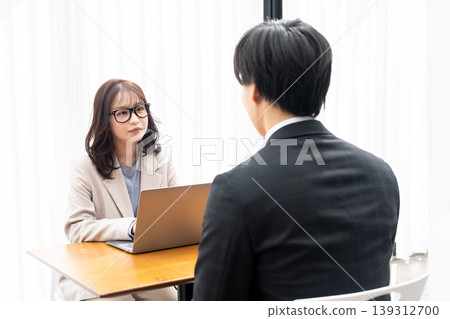 一位年輕女子正在給一位穿著西裝的男士提供建議。 一位年輕女子正在給一位穿著西裝的男士提供建議。 139312700