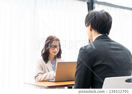 一位年輕女子正在給一位穿著西裝的男士提供建議。 139312701