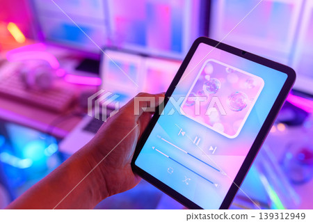 Hand holding a tablet with a music playback app 139312949