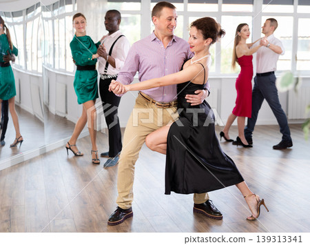Middle-aged man and woman practicing waltz in dancing studio Middle-aged man and woman practicing waltz in dancing studio 139313341