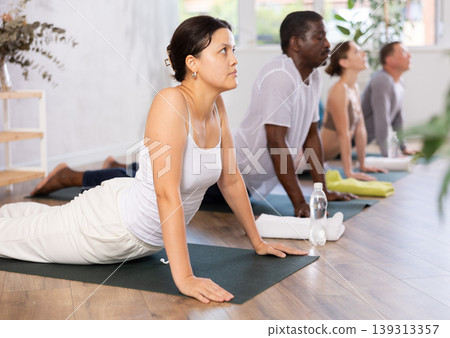 Asian woman doing stretching asana Urdhva Mukha Shvanasana in yoga studio Asian woman doing stretching asana Urdhva Mukha Shvanasana in yoga studio 139313357