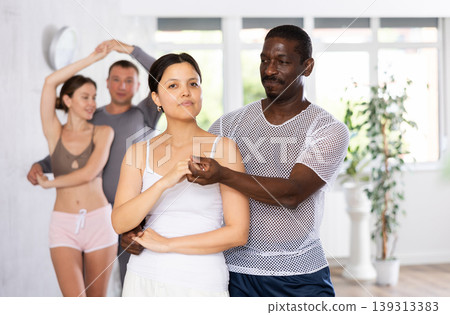 Smiling woman enjoying dance with African american male partner in dancing class Smiling woman enjoying dance with African american male partner in dancing class 139313383