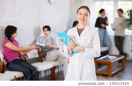 Young female nurse inviting patients in clinic Young female nurse inviting patients in clinic 139313420