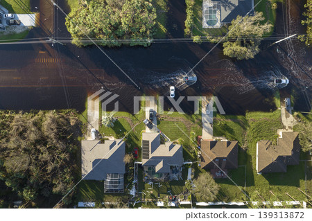 Flooded Florida road with evacuating cars and surrounded with water houses in suburban residential area. Consequences of hurricane natural disaster Flooded Florida road with evacuating cars and surrounded with water houses in suburban residential area. Consequences of hurricane natural disaster 139313872