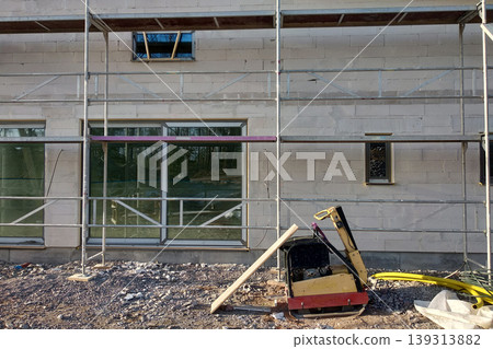 Facade of building made from white blocks with big windows under construction works. Facade of building made from white blocks with big windows under construction works. 139313882