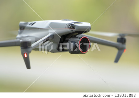 Drone quadcopter with digital camera and fast rotating propellers flying taking video and pictures Drone quadcopter with digital camera and fast rotating propellers flying taking video and pictures 139313898