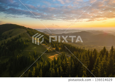 Dark pine forest illuminated with bright setting sun. Aerial view of colorful sunset in wild mountains. Beautiful nature landscape Dark pine forest illuminated with bright setting sun. Aerial view of colorful sunset in wild mountains. Beautiful nature landscape 139314029