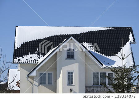 Closeup of house roof top covered with snow in cold winter. Tiled covering of building in wintertime weather Closeup of house roof top covered with snow in cold winter. Tiled covering of building in wintertime weather 139314072