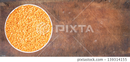 Bowl of uncooked dhal on wooden board 139314155
