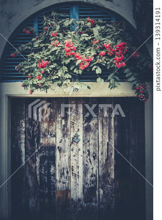 Old decay wooden door and flowers front view Old decay wooden door and flowers front view 139314191