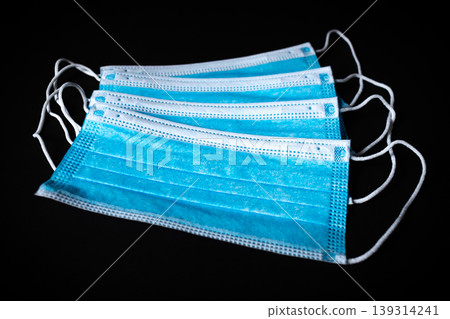 Four Surgical Face Masks lying on top of each in black background Four Surgical Face Masks lying on top of each in black background 139314241