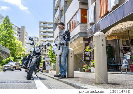 A male rider standing with his motorcycle in Kitayamada, Yokohama. A male rider standing with his motorcycle in Kitayamada, Yokohama. 139314728