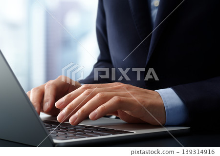 商務人士在辦公桌前使用筆記型電腦。特寫鏡頭:雙手和鍵盤。 商務人士在辦公桌前使用筆記型電腦。特寫鏡頭:雙手和鍵盤。 139314916