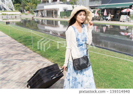 A woman enjoying a stroll through the city, pulling a suitcase. (Travel/Tourism Image) A woman enjoying a stroll through the city, pulling a suitcase. (Travel/Tourism Image) 139314940
