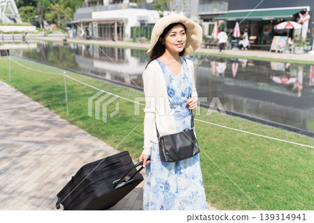 A woman enjoying a stroll through the city, pulling a suitcase. (Travel/Tourism Image) A woman enjoying a stroll through the city, pulling a suitcase. (Travel/Tourism Image) 139314941