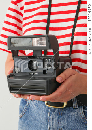 Person holds a vintage camera with a strap in hand 139314970