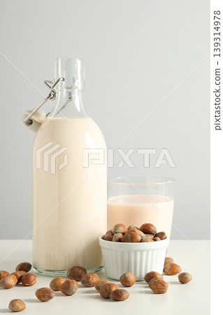 A glass bottle filled with nut milk and a cup beside it A glass bottle filled with nut milk and a cup beside it 139314978