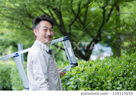 一張工人扛著梯子前往工地進行植樹或施工管理等工作的肖像照片,描繪了檢查工作。 一張工人扛著梯子前往工地進行植樹或施工管理等工作的肖像照片,描繪了檢查工作。 139315056