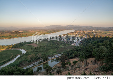 The Mekong River curves through farmland in Chiang Saen under soft light, with a winding road shaping a calm rural landscape pattern captured in 13 January 2023. The Mekong River curves through farmland in Chiang Saen under soft light, with a winding road shaping a calm rural landscape pattern captured in 13 January 2023. 139315517