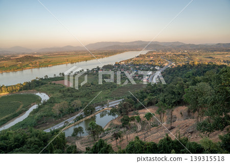 The Mekong River curves through farmland in Chiang Saen under soft light, with a winding road shaping a calm rural landscape pattern captured in 13 January 2023. The Mekong River curves through farmland in Chiang Saen under soft light, with a winding road shaping a calm rural landscape pattern captured in 13 January 2023. 139315518