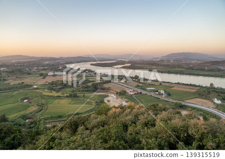 The Mekong River curves through farmland in Chiang Saen under soft light, with a winding road shaping a calm rural landscape pattern captured in 13 January 2023. The Mekong River curves through farmland in Chiang Saen under soft light, with a winding road shaping a calm rural landscape pattern captured in 13 January 2023. 139315519
