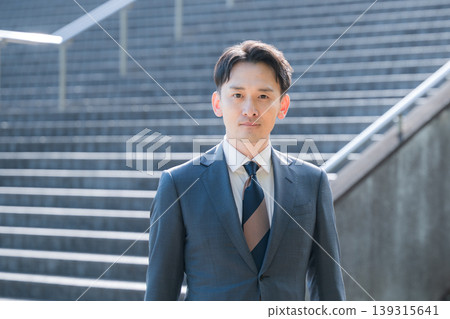 A business image of success and growth, featuring a sharp-looking salesman in a suit, gazing into the future against the backdrop of an office building and staircase. A business image of success and growth, featuring a sharp-looking salesman in a suit, gazing into the future against the backdrop of an office building and staircase. 139315641