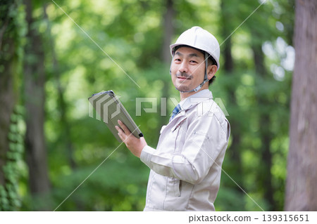 Portrait of field workers in forestry and construction management, wearing helmets and inspecting with tablets, demonstrating safety management and DX operations. Portrait of field workers in forestry and construction management, wearing helmets and inspecting with tablets, demonstrating safety management and DX operations. 139315651