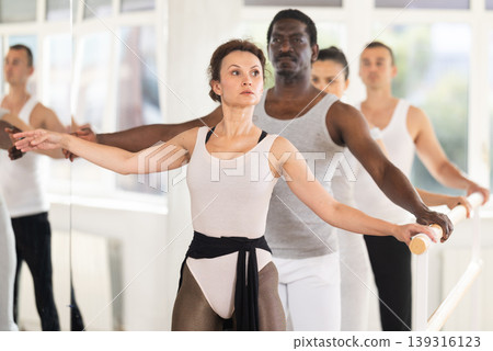 Woman mastering second ballet position at barre in choreographic studio Woman mastering second ballet position at barre in choreographic studio 139316123