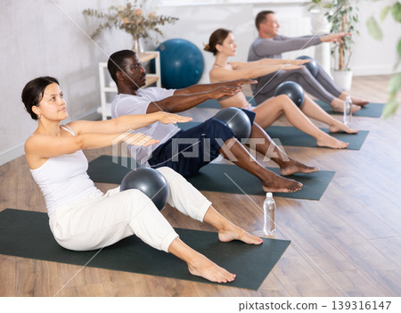 Young woman practicing pilates with soft ball in group 139316147