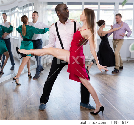 Woman dances incendiary tango with African man partner during choreography lesson Woman dances incendiary tango with African man partner during choreography lesson 139316171