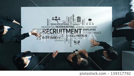 Business Team Discussing Recruitment Strategies Around Table with Relevant Keywords and Concepts in Modern Office Setting. Amity Business Team Discussing Recruitment Strategies Around Table with Relevant Keywords and Concepts in Modern Office Setting. Amity 139317792