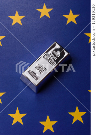 A silver bar, white metal against a backdrop of EU flag, as a concept. A silver bar A silver bar, white metal against a backdrop of EU flag, as a concept. A silver bar 139319130