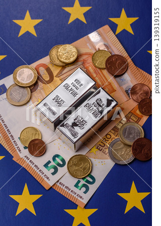 A silver bar, white metal against a backdrop of EU flag, as a concept. A silver bar A silver bar, white metal against a backdrop of EU flag, as a concept. A silver bar 139319155