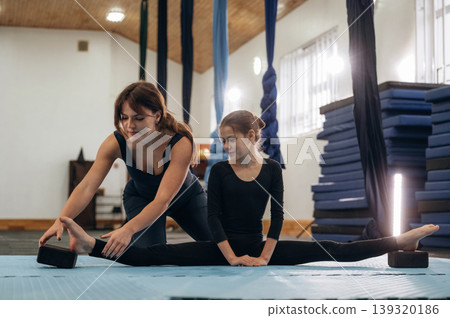 Professional help, learning. Female instructor helping a child practice yoga in a fitness studio Professional help, learning. Female instructor helping a child practice yoga in a fitness studio 139320186