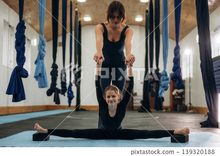 Professional help, learning. Female instructor helping a child practice yoga in a fitness studio Professional help, learning. Female instructor helping a child practice yoga in a fitness studio 139320188