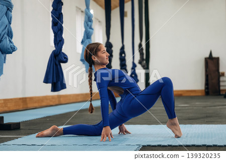 Legs stretching exercises. Child practicing yoga on a mat in a fitness studio Legs stretching exercises. Child practicing yoga on a mat in a fitness studio 139320235