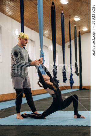 Man is teaching. Male instructor assisting a child during yoga practice in a fitness studio 139320285