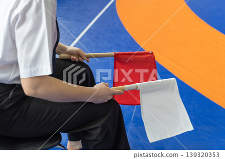 Martial arts referee holding red and white scoring flags Martial arts referee holding red and white scoring flags 139320353