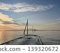 A sunset view of the Nagabeta Seashore Road in Kumamoto, with utility poles stretching out into the sea. 139320672