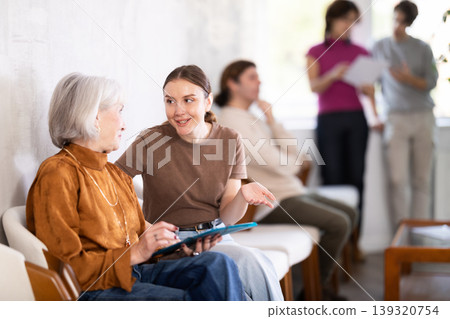 Mature woman talking to young woman while sitting in waiting area Mature woman talking to young woman while sitting in waiting area 139320754
