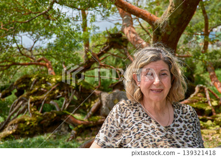An elderly woman poses next to an ancient tree in the Furnas Botanical Garden in the Azores. 139321418