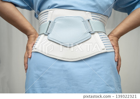 Asian senior pain back wearing elastic support belt with walker. 139322321
