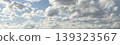 A panoramic photo of a blue sky with clouds and an airplane. 139323567