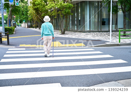 一位老婦人拄著拐杖走過行人穿越道，這是她的背影。 139324239