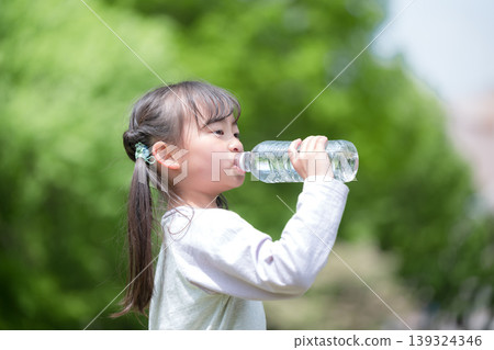特寫：一名小學生在綠樹環繞中喝水，以預防中暑。 139324346
